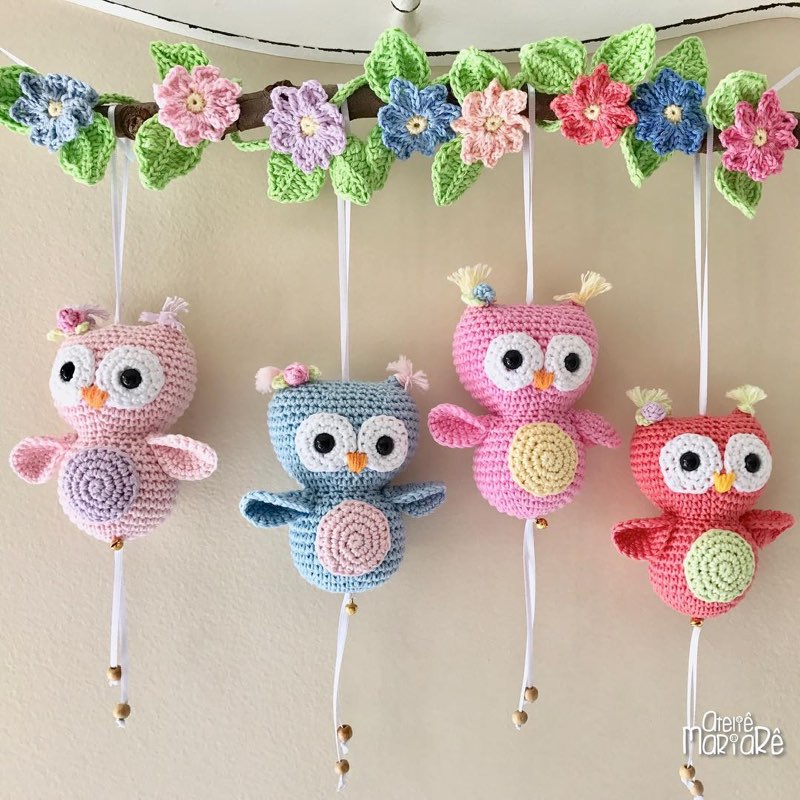 Móbile de berço com quatro corujinhas coloridas de crochê amigurumi penduradas em galho floral
