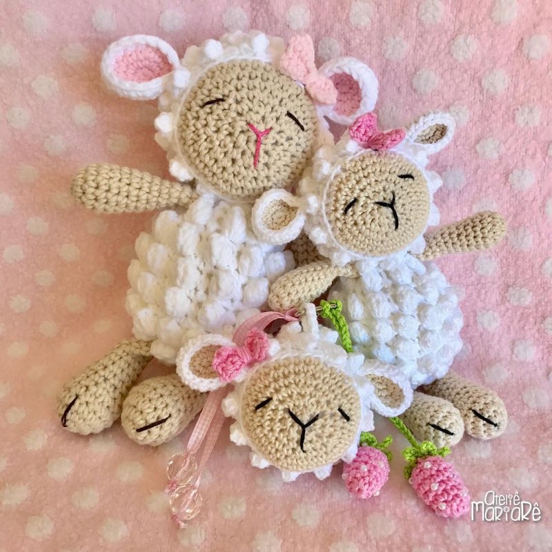 Duas ovelhinhas de crochê amigurumi penduradas como enfeite, com laço rosa e flores