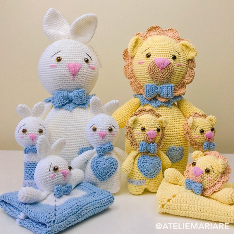 Família de leões e coelhos de crochê amigurumi com laços azuis, incluindo mantinhas de apego