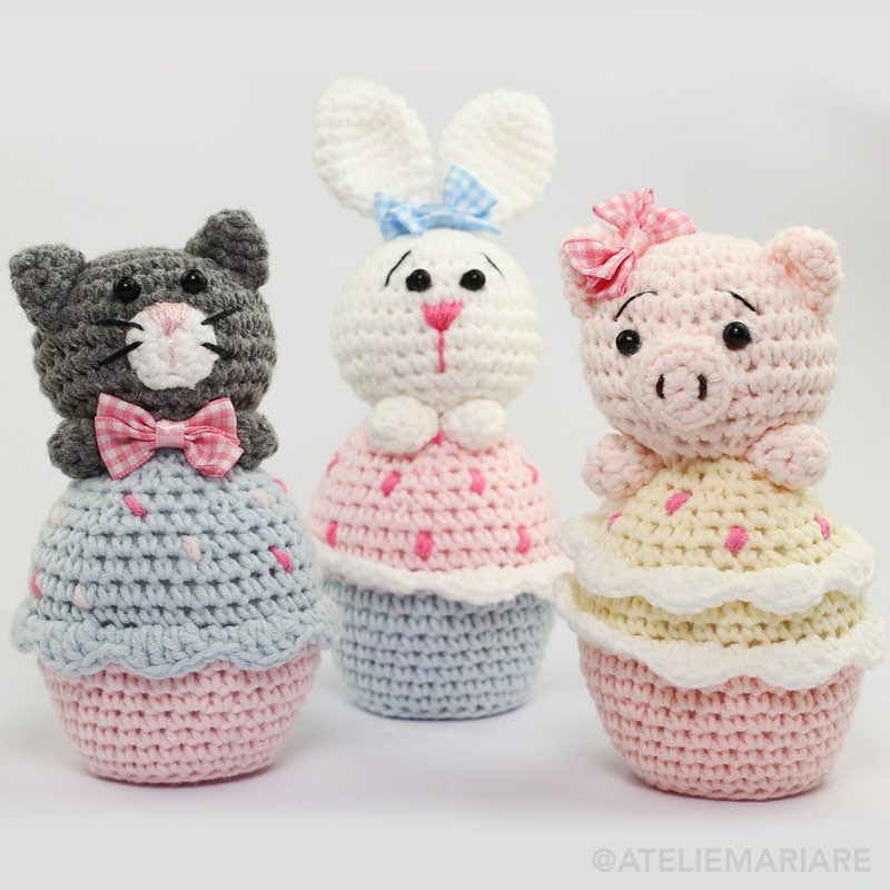 Trio de bichinhos de crochê amigurumi em formato de cupcake: um gatinho cinza, uma coelhinha branca e uma porquinha rosa
