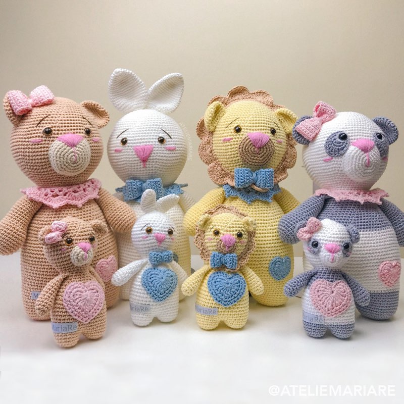 Ursinho grande de crochê ao lado de três bichinhos pequenos (urso, coelho e leão) com mantinhas de apego