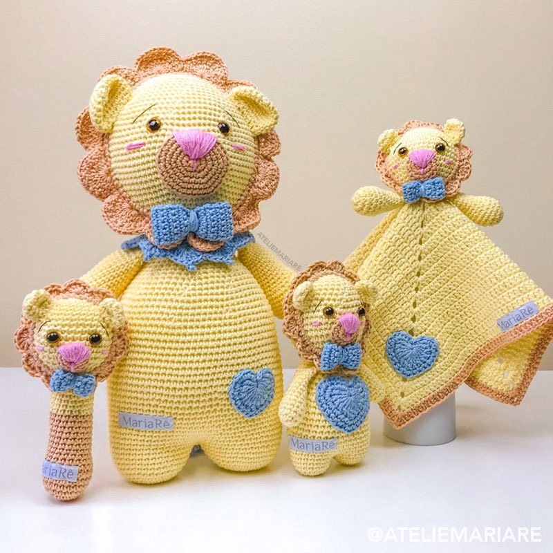 Família de leões amarelos de crochê amigurumi em tamanhos diferentes, com mantinha de apego