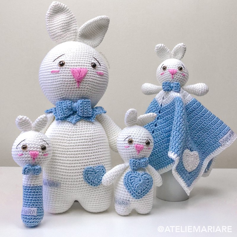 Família de coelhos brancos de crochê amigurumi com laços azuis e mantinha de apego